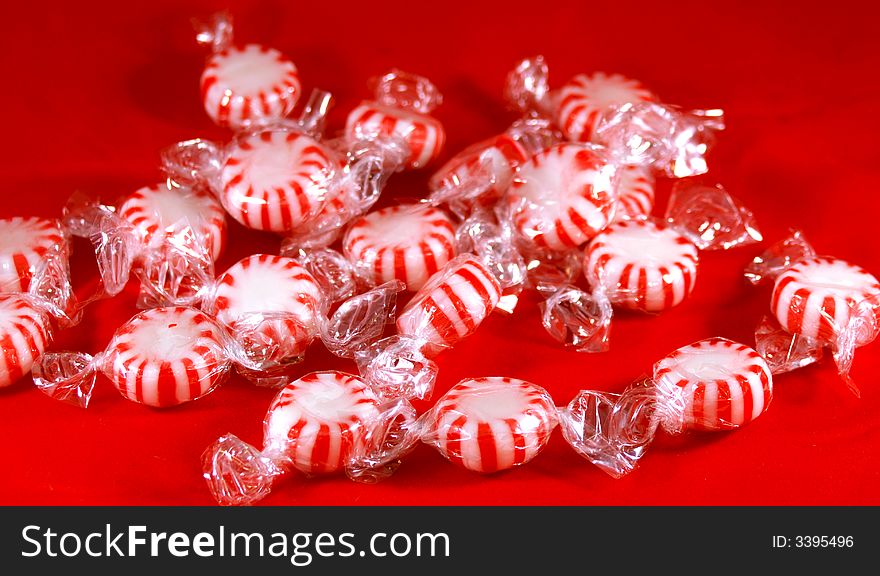 A pile of red and white peppermint candy on a red background.
