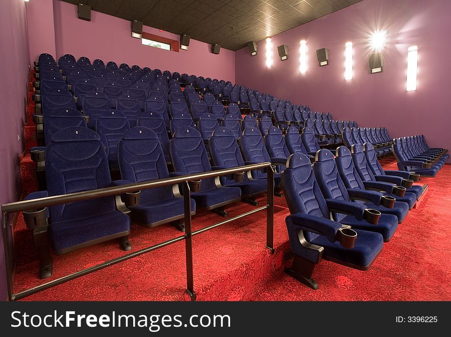 Empty cinema auditorium, blue chairs red carpet