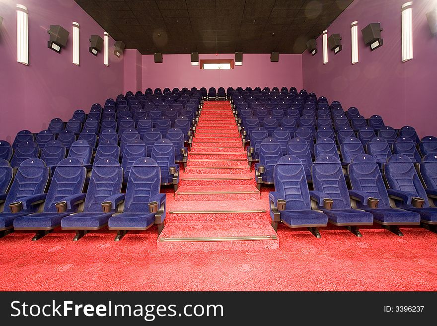 Empty cinema auditorium, blue chairs red carpet