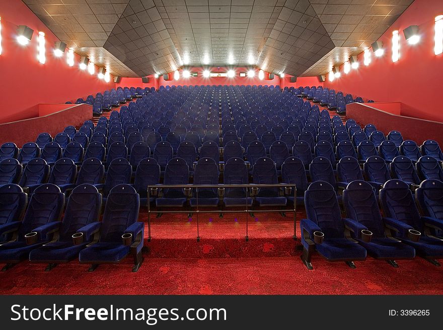 Empty cinema auditorium, blue chairs red carpet