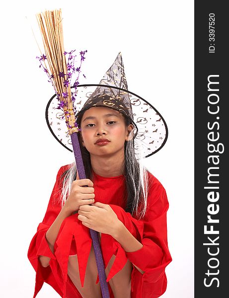 A young girl dressed in a witch costume sitting down