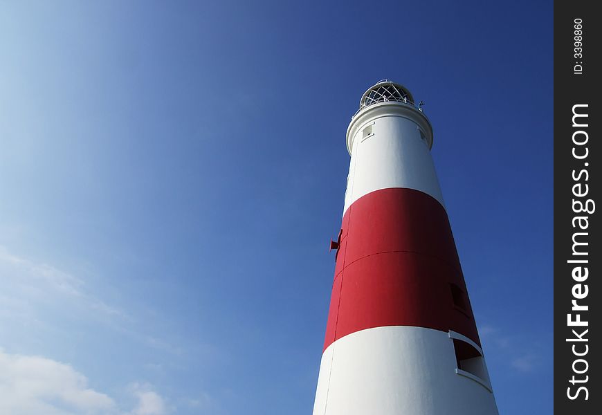 Looking up at Portland Bill Lighthouse, Dorset, England, with blue sky behind