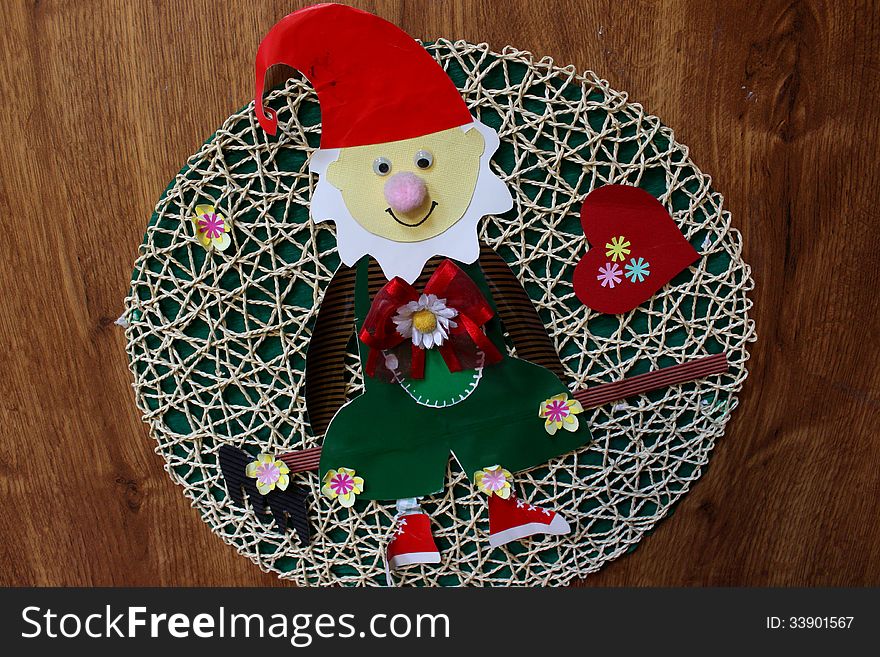 Elf made from colored paper on a braided background placed on wooden door