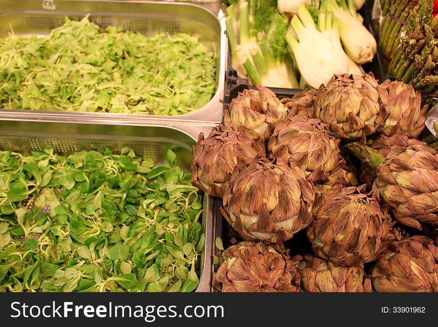 Artichoke and salad placed in stainless steel containers in supermarket