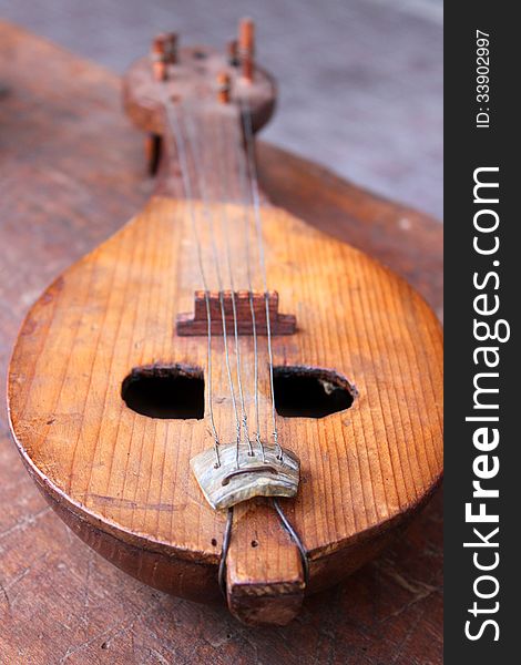 Antique old-fashioned obsolete mandolin on wooden table. Antique old-fashioned obsolete mandolin on wooden table