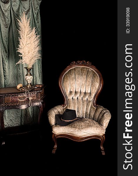 Antique chair next to an old table with a pistol and powder horn on it. Antique chair next to an old table with a pistol and powder horn on it