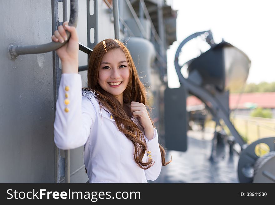 Pretty woman sailor posing with metal ladder on battleship