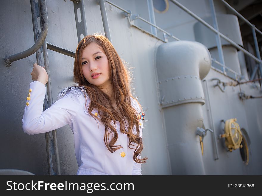 Pretty woman sailor posing with steel ladder on battleship