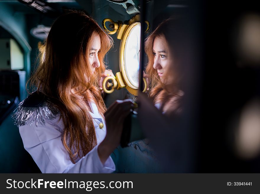 Pretty woman sailor looking through window of battleship