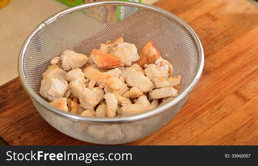 A strainer of freshly cooked chicken cut up in bite size pieces. A strainer of freshly cooked chicken cut up in bite size pieces.
