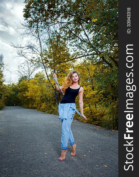 Beautiful pin-up girl in denim overalls and a T-shirt outdoors