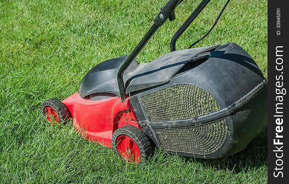 Modern lawn mower on a green lawn. Mowing the lawn with an electric mower with a container to collect the cut grass.