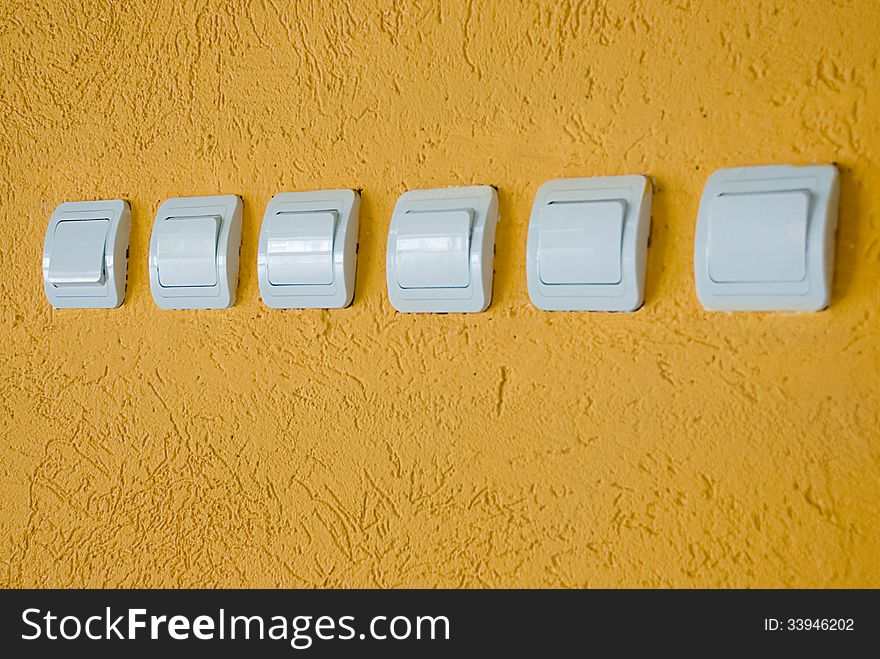 Row of white electric switches on the orange wall