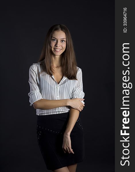 Smiling girl in white blouse and black skirt on black background. Smiling girl in white blouse and black skirt on black background