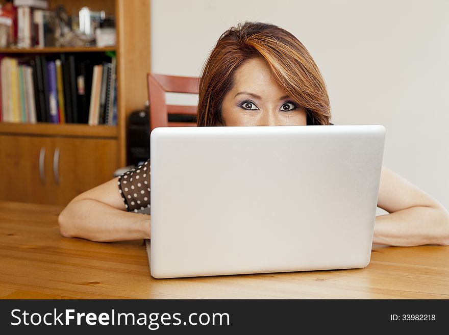 Shy Asian business woman hiding in her office