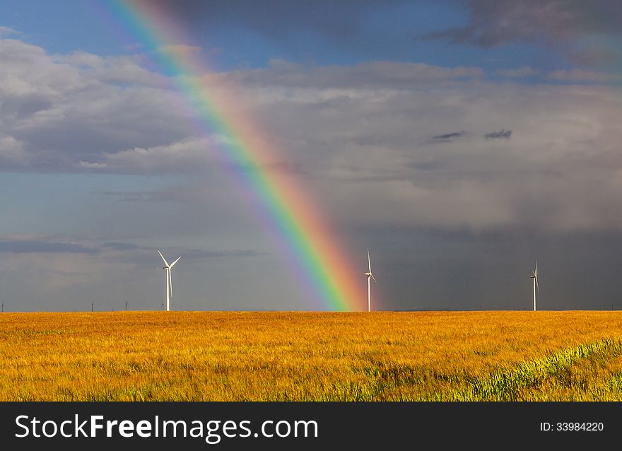 Beautiful rainbow over a field of cereals with wind turbines in the distance. Beautiful rainbow over a field of cereals with wind turbines in the distance.