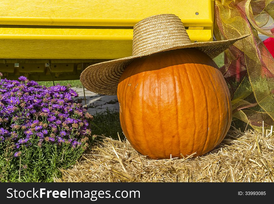 Pumpkin and hat on hay with flowers