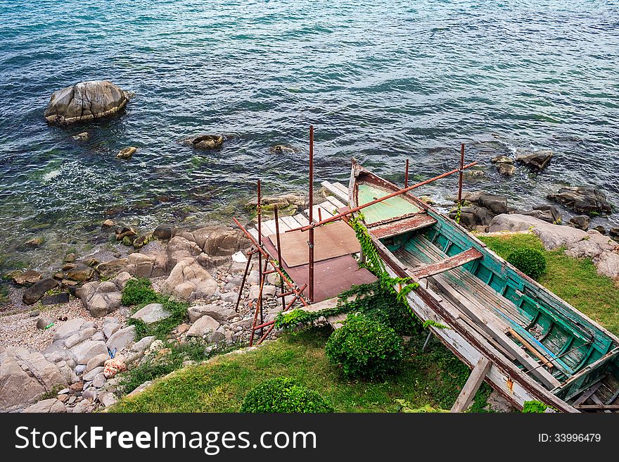 Old broken boat on the rocky shore waiting repair for a long time. Old broken boat on the rocky shore waiting repair for a long time