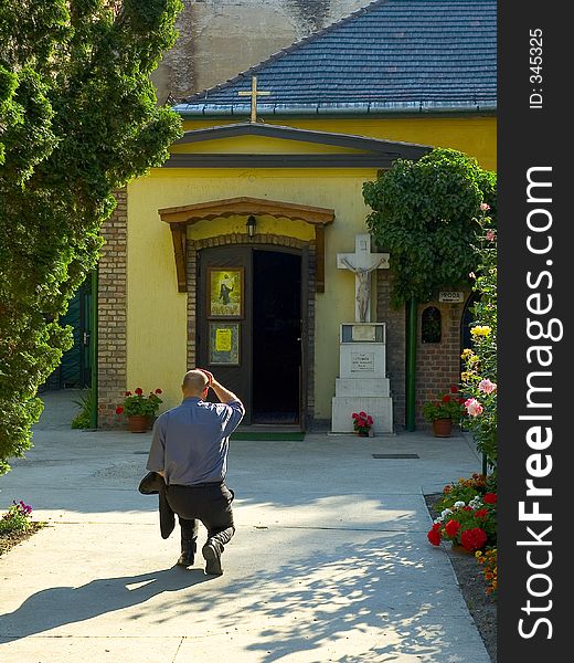 Man kneeling infront of small catholic church. Man kneeling infront of small catholic church