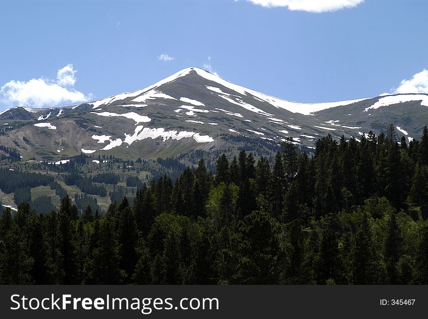 A snow capped mountain peak juts into the blue Colorado sky. A snow capped mountain peak juts into the blue Colorado sky.