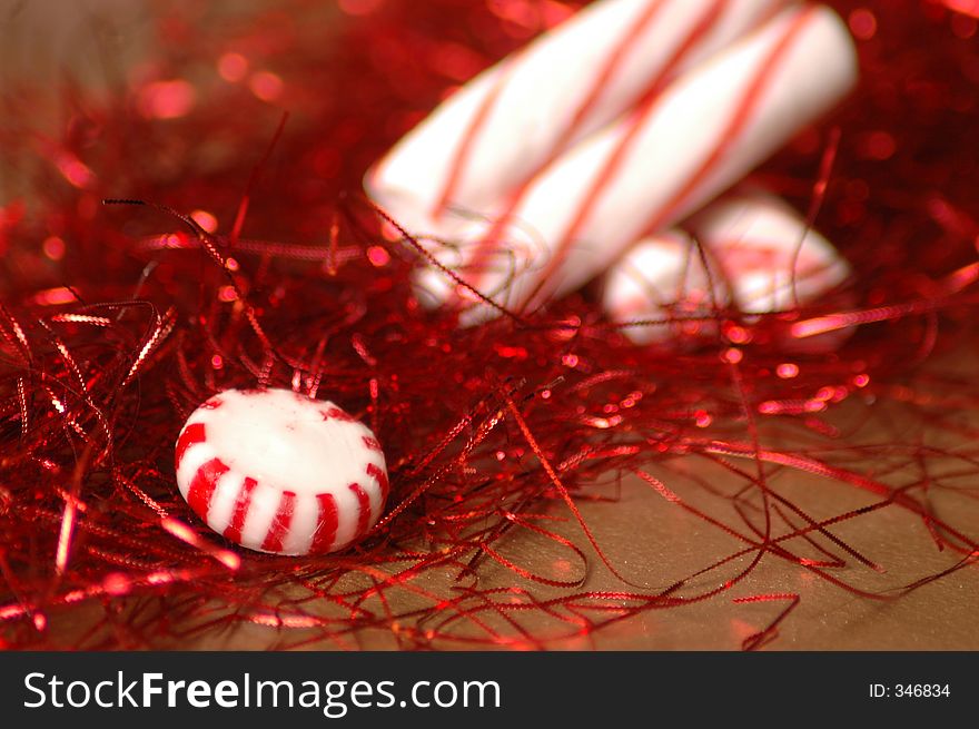 Holiday still life with red tinsel and round peppermint candy and sticks shallow depth of field. Holiday still life with red tinsel and round peppermint candy and sticks shallow depth of field