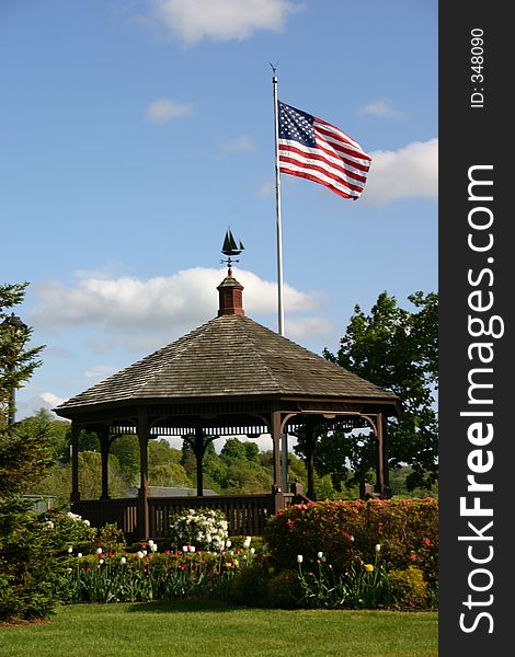 A parks gazebo flying the american flag over it.