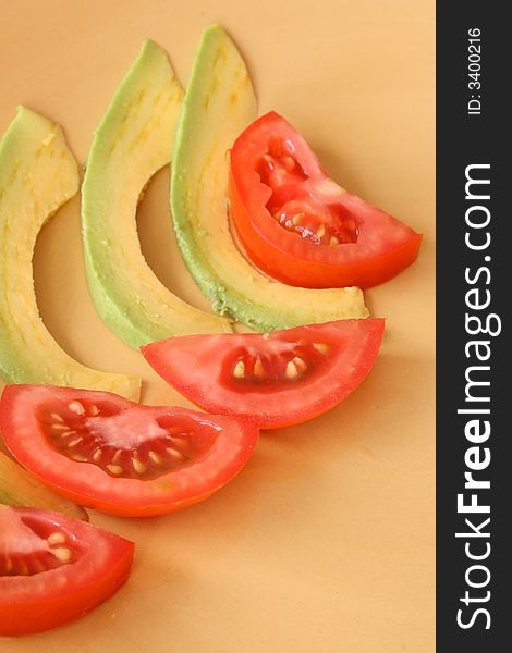 Tomato and Avocado Slices on a yellow plate. Tomato and Avocado Slices on a yellow plate