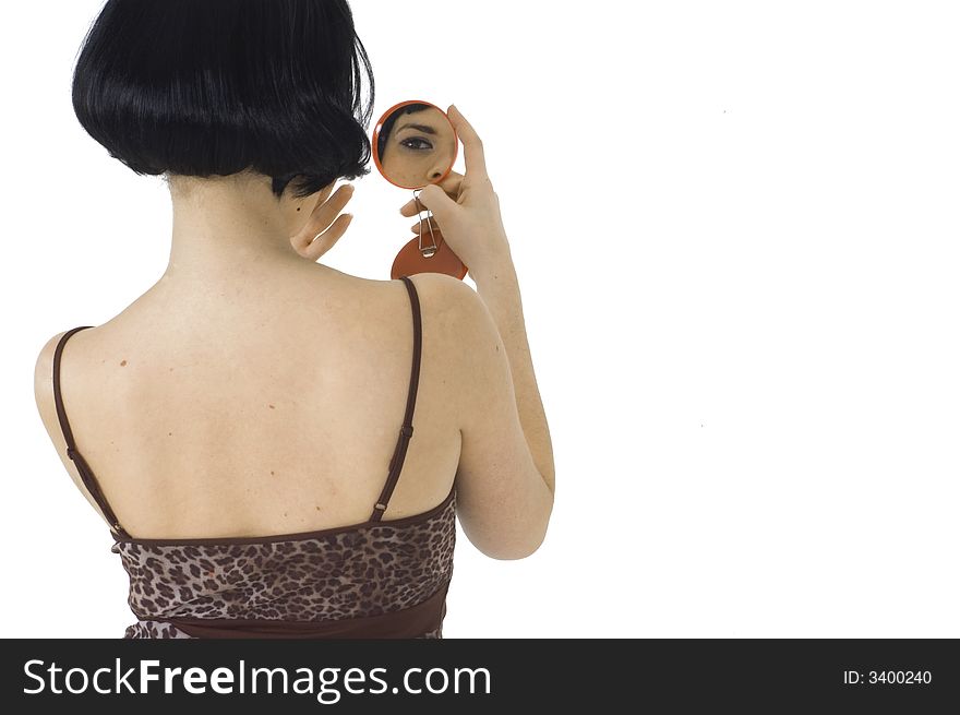 Woman dressed with spotted top, dark hair, eye- liner make- up. She is using a small round mirror to control if everything is ok. Woman dressed with spotted top, dark hair, eye- liner make- up. She is using a small round mirror to control if everything is ok.