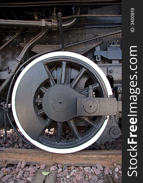 An antique steam engine's wheel sitting on a piece of track. An antique steam engine's wheel sitting on a piece of track