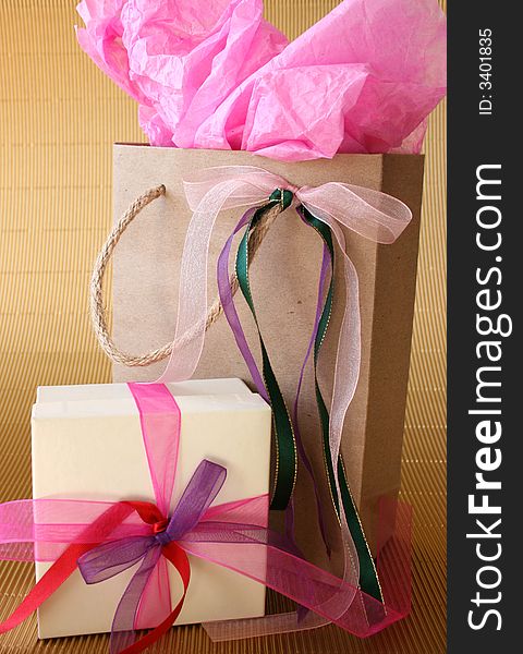 Cream colored gift box and brown gift bag with ribbons. Cream colored gift box and brown gift bag with ribbons