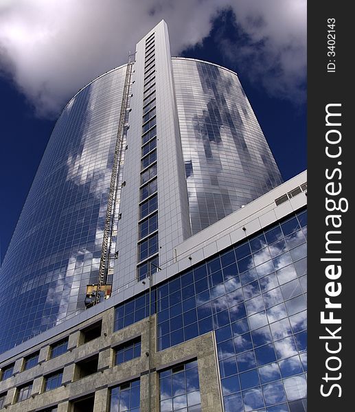 High-altitude building with mirror windows in which the blue sky and white clouds is reflected. High-altitude building with mirror windows in which the blue sky and white clouds is reflected.