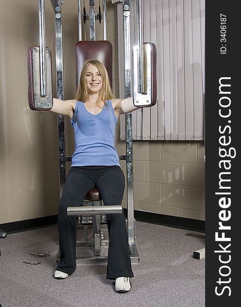 Beautiful young blond woman doing pectoral muscle exercise in a fitness location using gym equipment. Beautiful young blond woman doing pectoral muscle exercise in a fitness location using gym equipment.