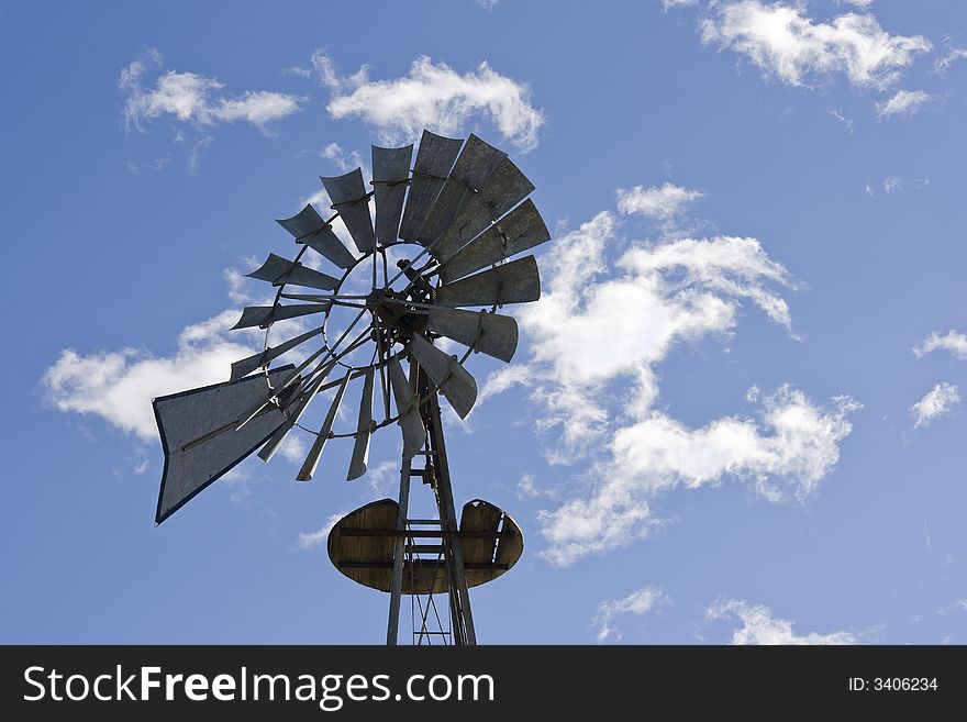Horizontal photo of antique style windmill against a blue sky with white clouds often found on small farms. Horizontal photo of antique style windmill against a blue sky with white clouds often found on small farms.