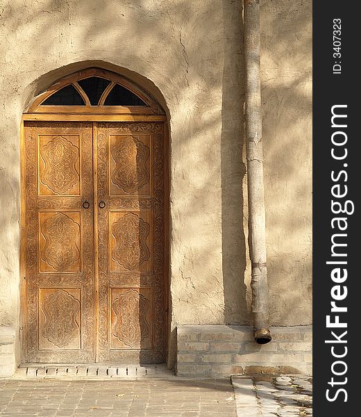 Traditional Central Asian door with beautiful shadows on an old-fashioned mudbrick wall. Traditional Central Asian door with beautiful shadows on an old-fashioned mudbrick wall.