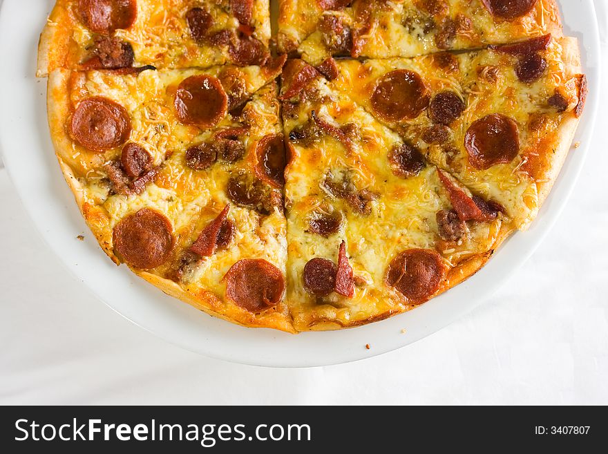 Detail shot of hot fresh pepperoni pizza isolated against a white background with great colors and depth of field. Room for text. Detail shot of hot fresh pepperoni pizza isolated against a white background with great colors and depth of field. Room for text.