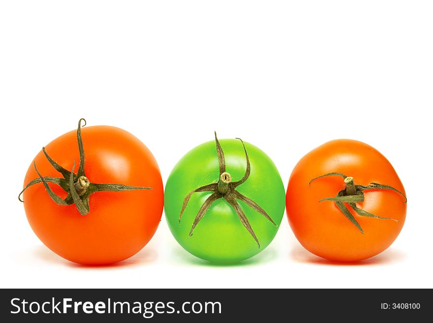 Three top viewed tomatoes lying on the same plane on white background . two of them are red while the middle one is green. Three top viewed tomatoes lying on the same plane on white background . two of them are red while the middle one is green.