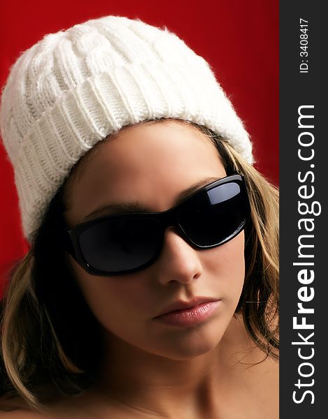 Portrait of a beautiful woman with a cap and some sunglasses against red background. Portrait of a beautiful woman with a cap and some sunglasses against red background