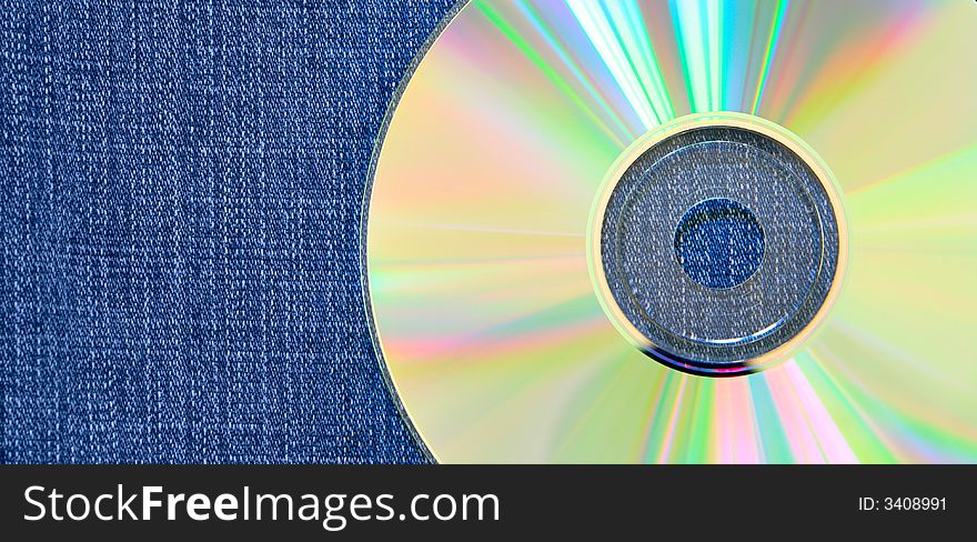 Raibow compact disk over blue jean background. Raibow compact disk over blue jean background