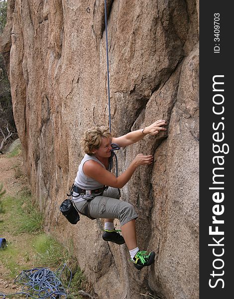 A woman climber starting into a really difficult climb. A woman climber starting into a really difficult climb.