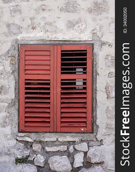 Window with red shutters in grey stone building