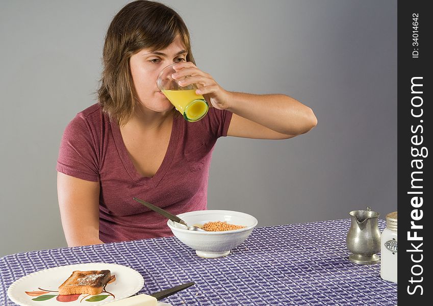 Young woman, 20s, drinking juice with a gluten-free breakfast. Young woman, 20s, drinking juice with a gluten-free breakfast