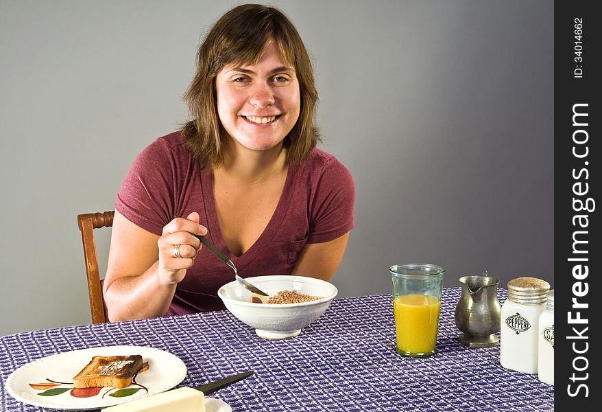 Young woman, 20s, enjoys flax cereal and gluten-free toast for breakfast. Young woman, 20s, enjoys flax cereal and gluten-free toast for breakfast