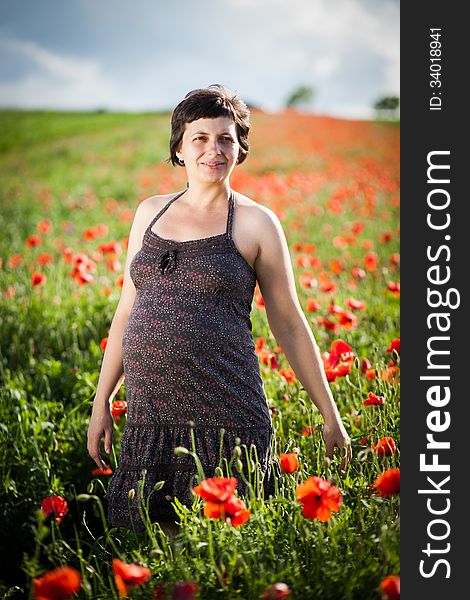 Pregnant happy woman in a flowering poppy field outdoors