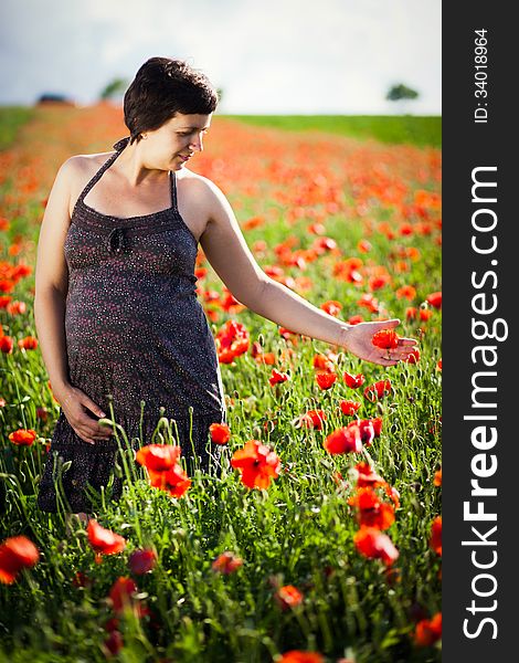 Pregnant happy woman in a flowering poppy field outdoors