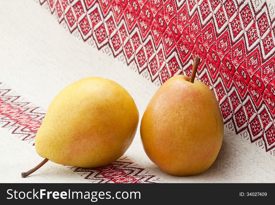 Two ripe pears on a linen napkin with ornament