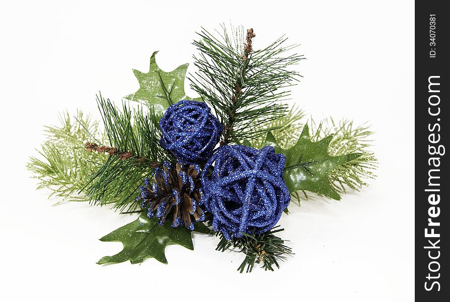 Christmas ornamental glittery blue balls and pinecone on spruce branches against a white background. Christmas ornamental glittery blue balls and pinecone on spruce branches against a white background