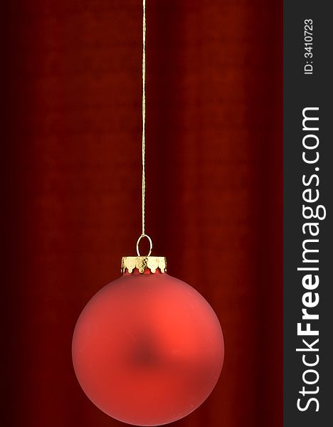 An image of a red Christmas ornament on a burgundy background