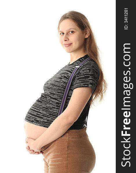 Happy young pregnant woman looking on a viewer and smiling. She is in black T-short , brown velvet pants with suspenders. Her hands support belly. On white background. Happy young pregnant woman looking on a viewer and smiling. She is in black T-short , brown velvet pants with suspenders. Her hands support belly. On white background