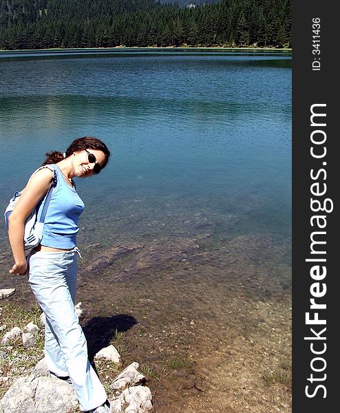 A girl posing at some rocks at the bank of a glacier lake named Black Lake at the mountain of Durmitor, Montenegro. A girl posing at some rocks at the bank of a glacier lake named Black Lake at the mountain of Durmitor, Montenegro