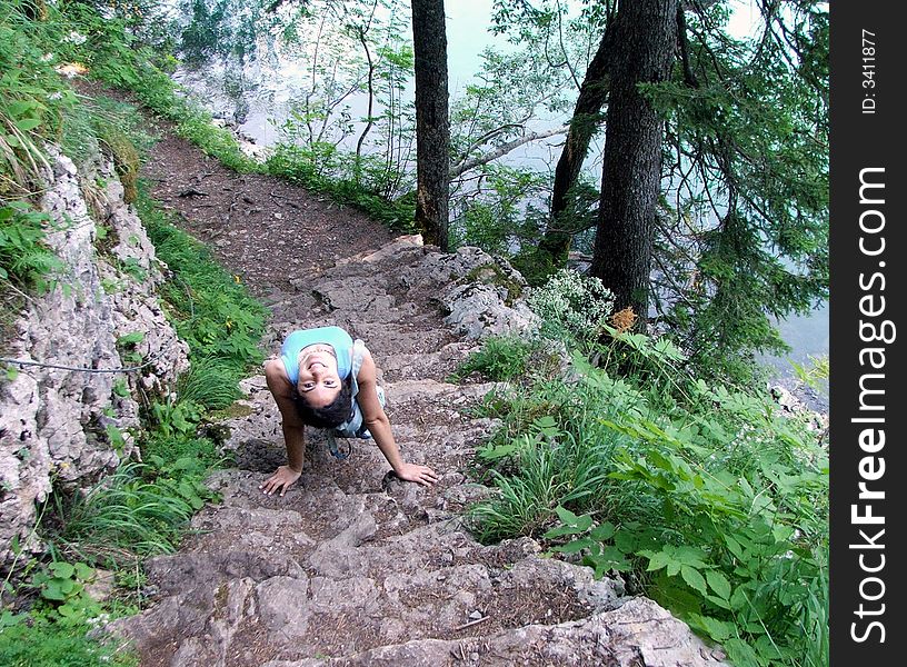 A girl stretching upside down on rock stairs at the lake bank. A girl stretching upside down on rock stairs at the lake bank